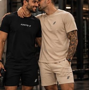 Dois homens abraçados, um de camiseta preta e outro de camiseta areia