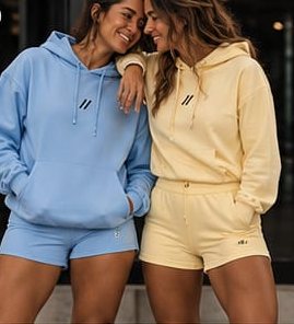 Duas mulheres abraçadas com moletons azul e manteiga